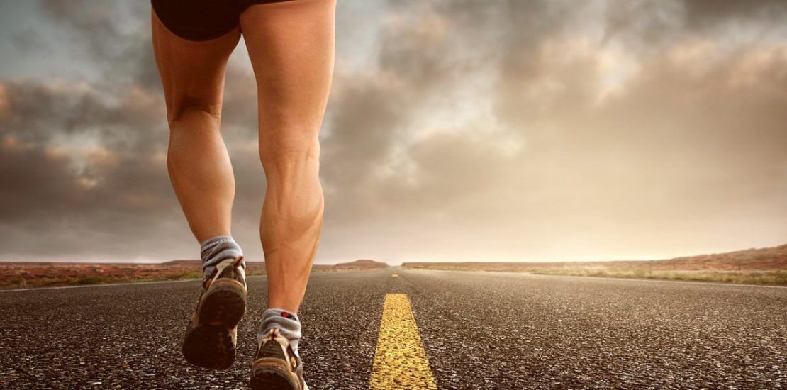 A person is running down a road with a cloudy sky in the background.