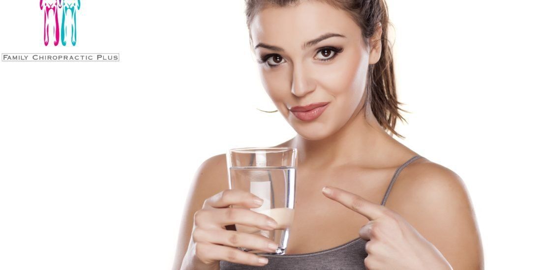 A woman is holding a glass of water and pointing at it.