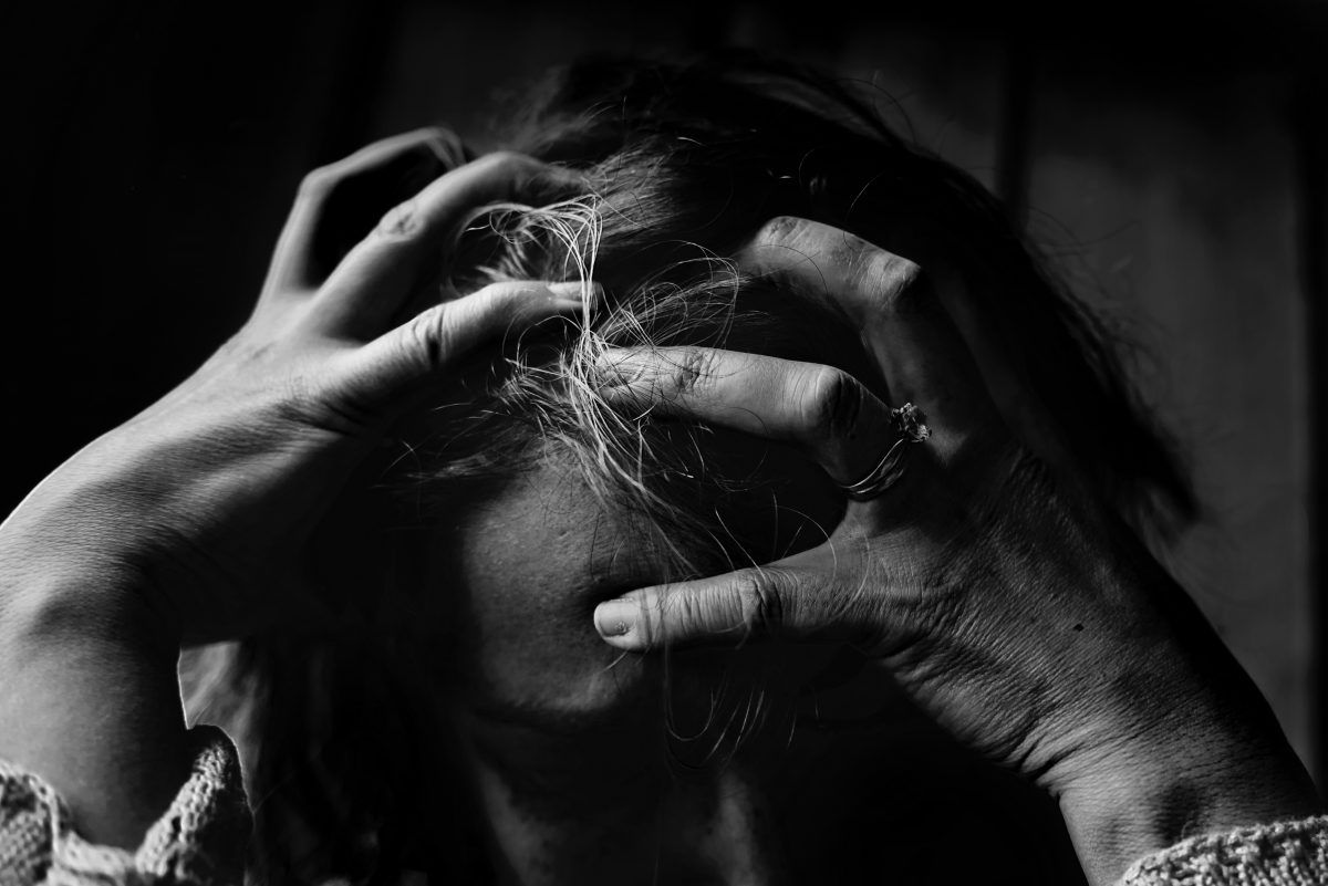 A woman is holding her head with her hands in a black and white photo.