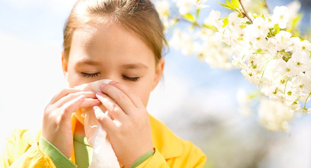 A young girl is blowing her nose with a napkin.