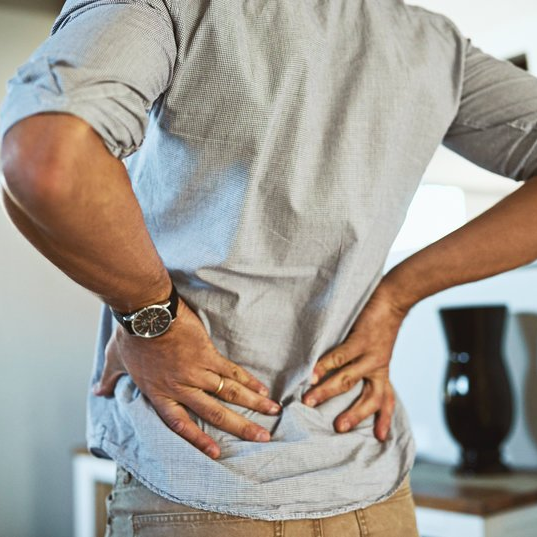 A man wearing a watch is holding his back in pain