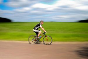 A man is riding a bike on a dirt road.