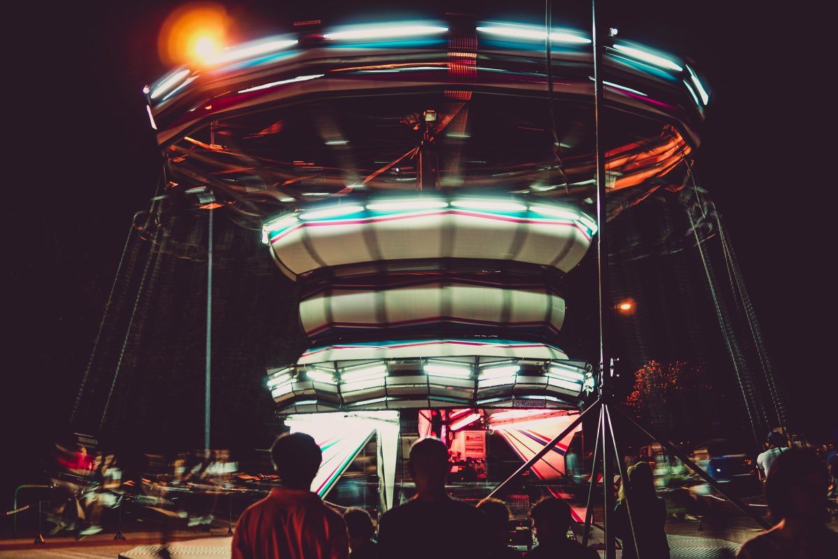 A group of people are standing around a carnival ride at night.