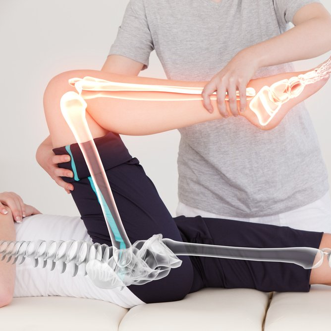 A person laying on a bed with a skeleton behind them