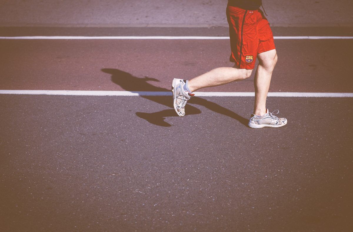 A man in red shorts is running on a track.