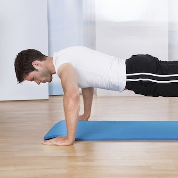 A man is doing push ups on a blue mat