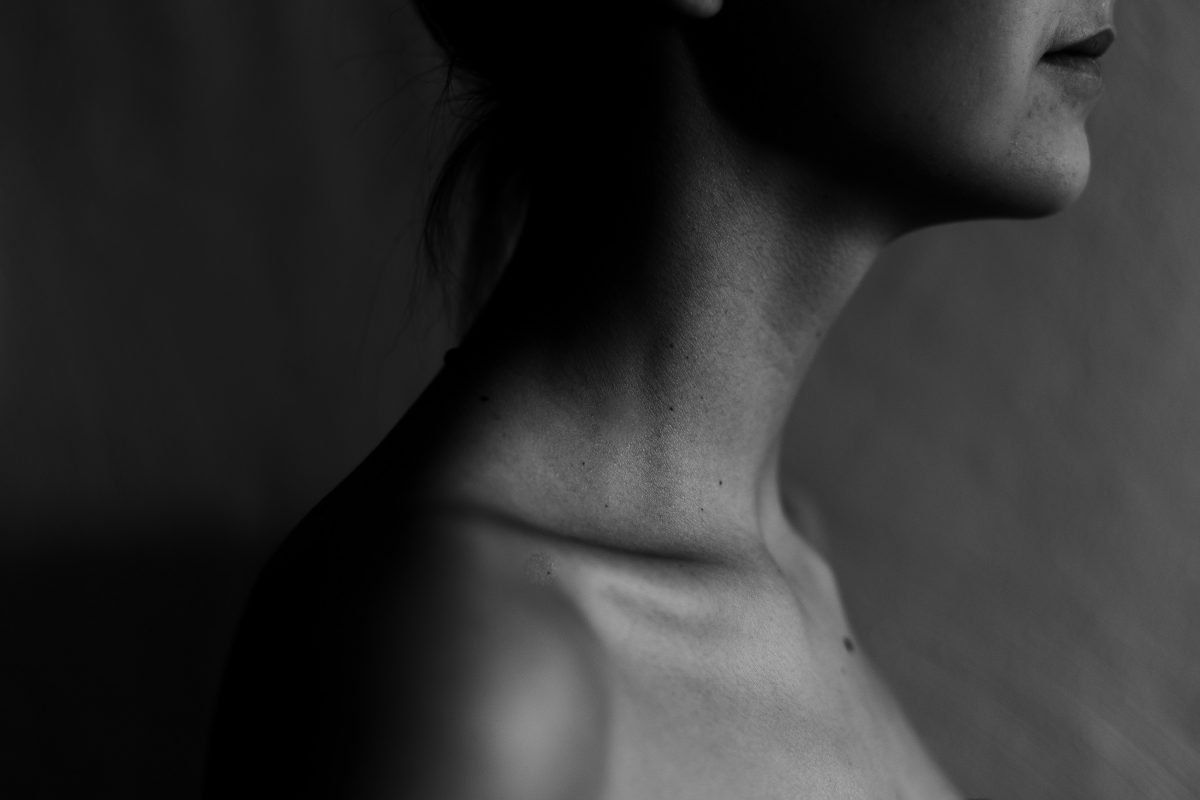 A black and white photo of a woman 's neck and shoulder.