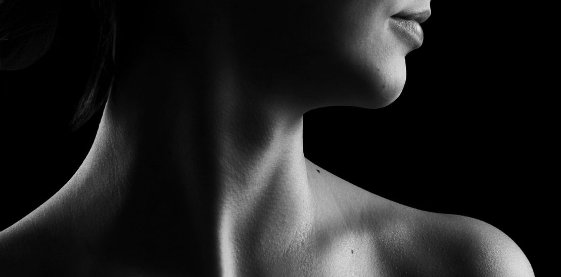 A black and white photo of a woman 's neck and shoulder.