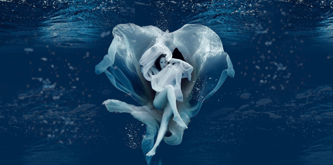 A woman is floating in the water with a flower in the shape of a heart.