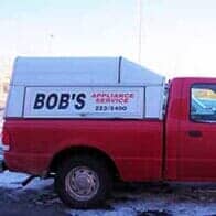 Red Van — Appliance Repair in Collins, CO Red pickup truck with a white service cap labeled “BOB’S” parked in snow.