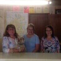 Red Service — Appliance Repair in Collins, CO Three people and a small dog stand behind a counter in a dim room with maps on the wall.