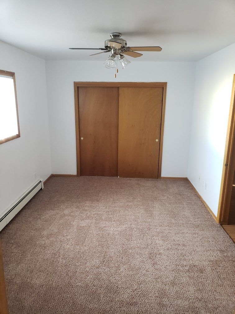 Interior of long narrow room with large sliding door closet on far end