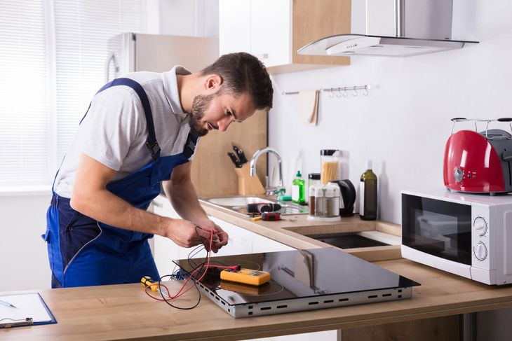 Technician Repairing Induction Stove — Kitty Hawk, NC — Coastland Appliance LLC Technician Repairing Induction Stove — Kitty Hawk, NC — Coastland Appliance LLC