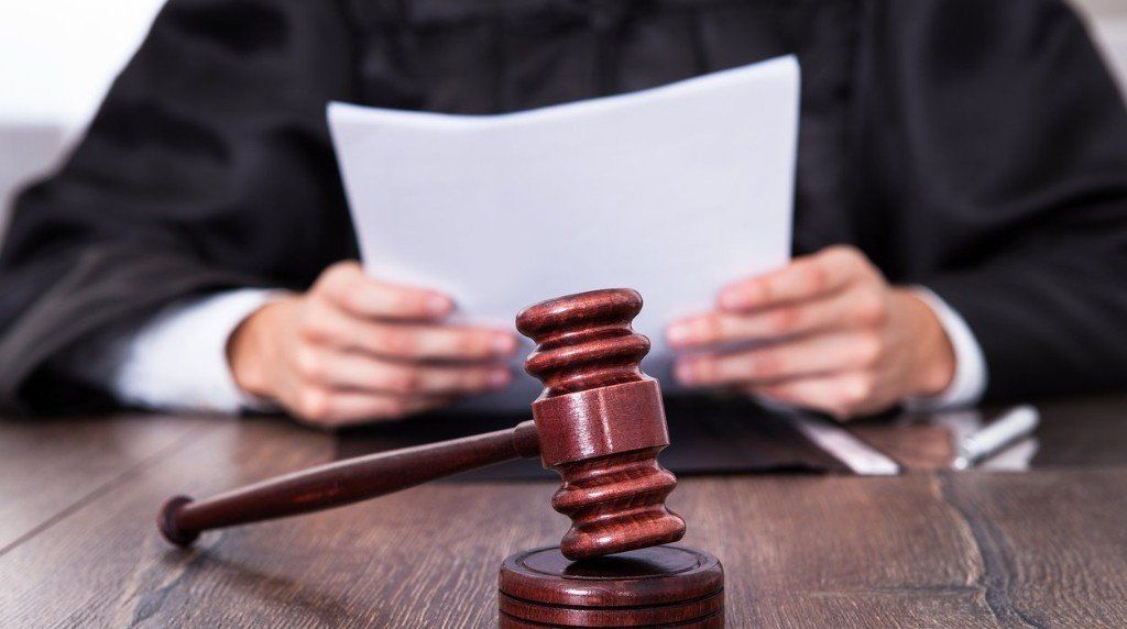 a judge is holding a piece of paper in front of a wooden gavel