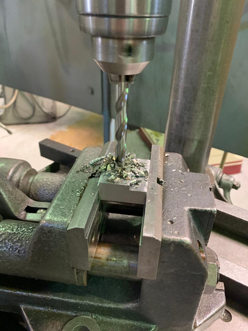 A drill bit is being used to drill a hole in a piece of metal.