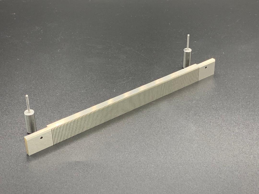 A piece of metal with a comb on it is sitting on a table.