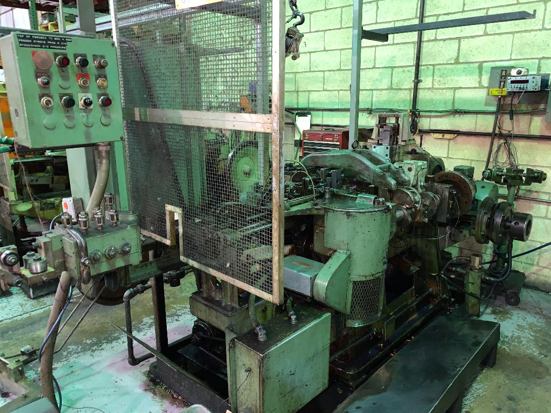 A machine is sitting in a warehouse with a fence around it.