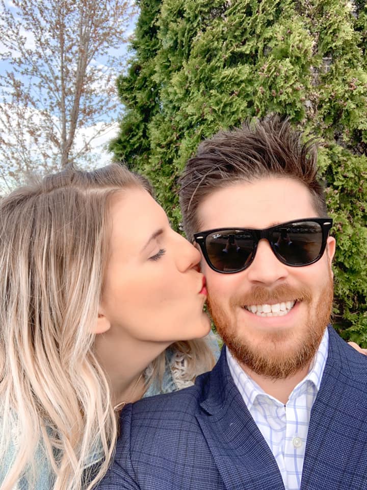 A woman is kissing a man on the cheek while wearing sunglasses.