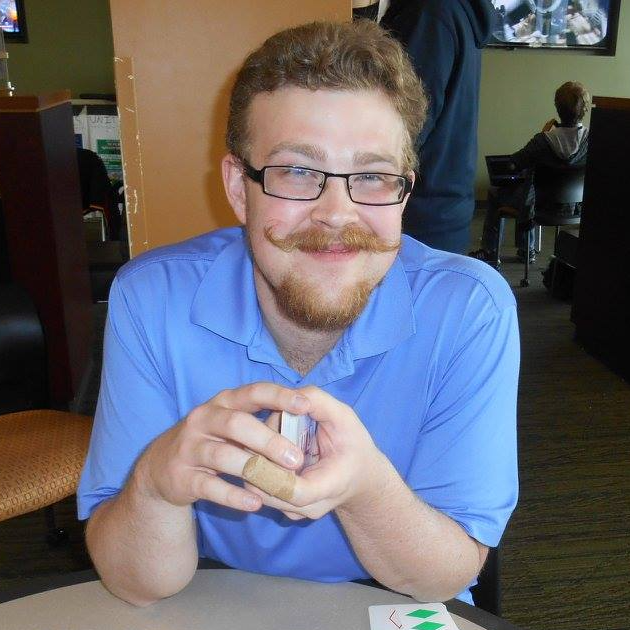 A man with glasses and a mustache is sitting at a table