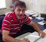 A man in a red striped shirt is sitting at a desk.