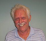 A man with gray hair and a mustache is smiling for the camera.