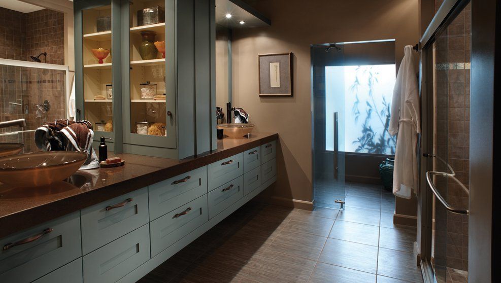 A bathroom with blue cabinets and a glass shower door