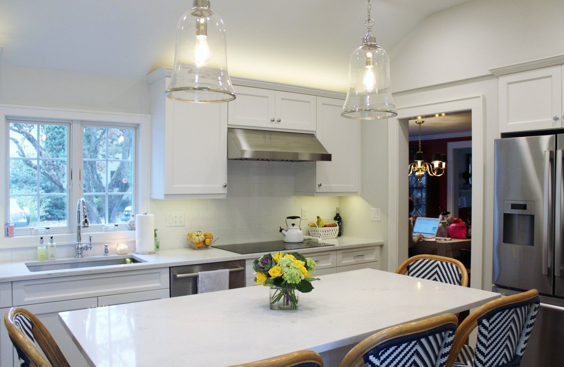 A kitchen with a table and chairs and a vase of flowers on it.