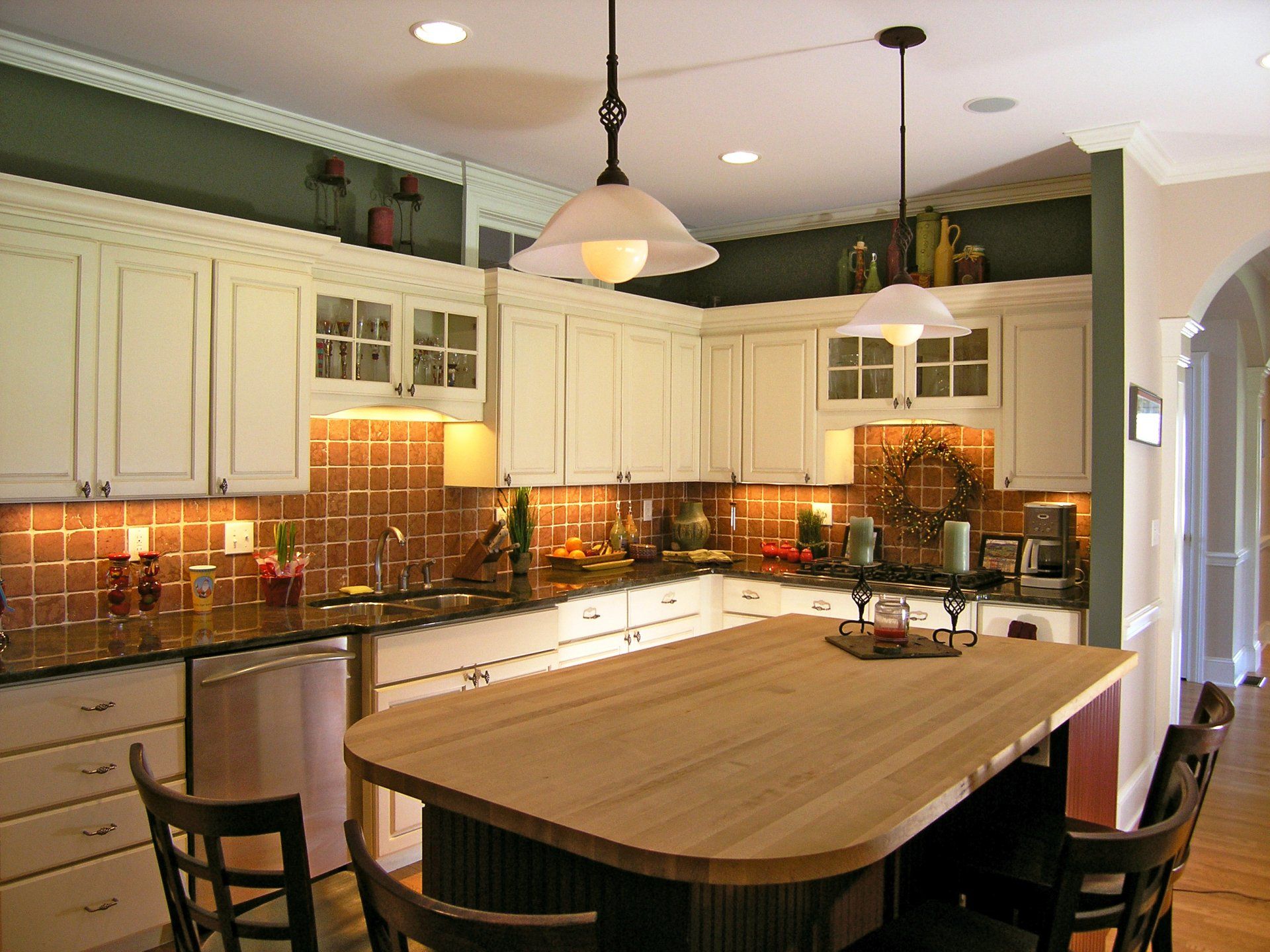 Modern kitchen with cream cabinets, warm tile backsplash, and a large central island with wood countertop.