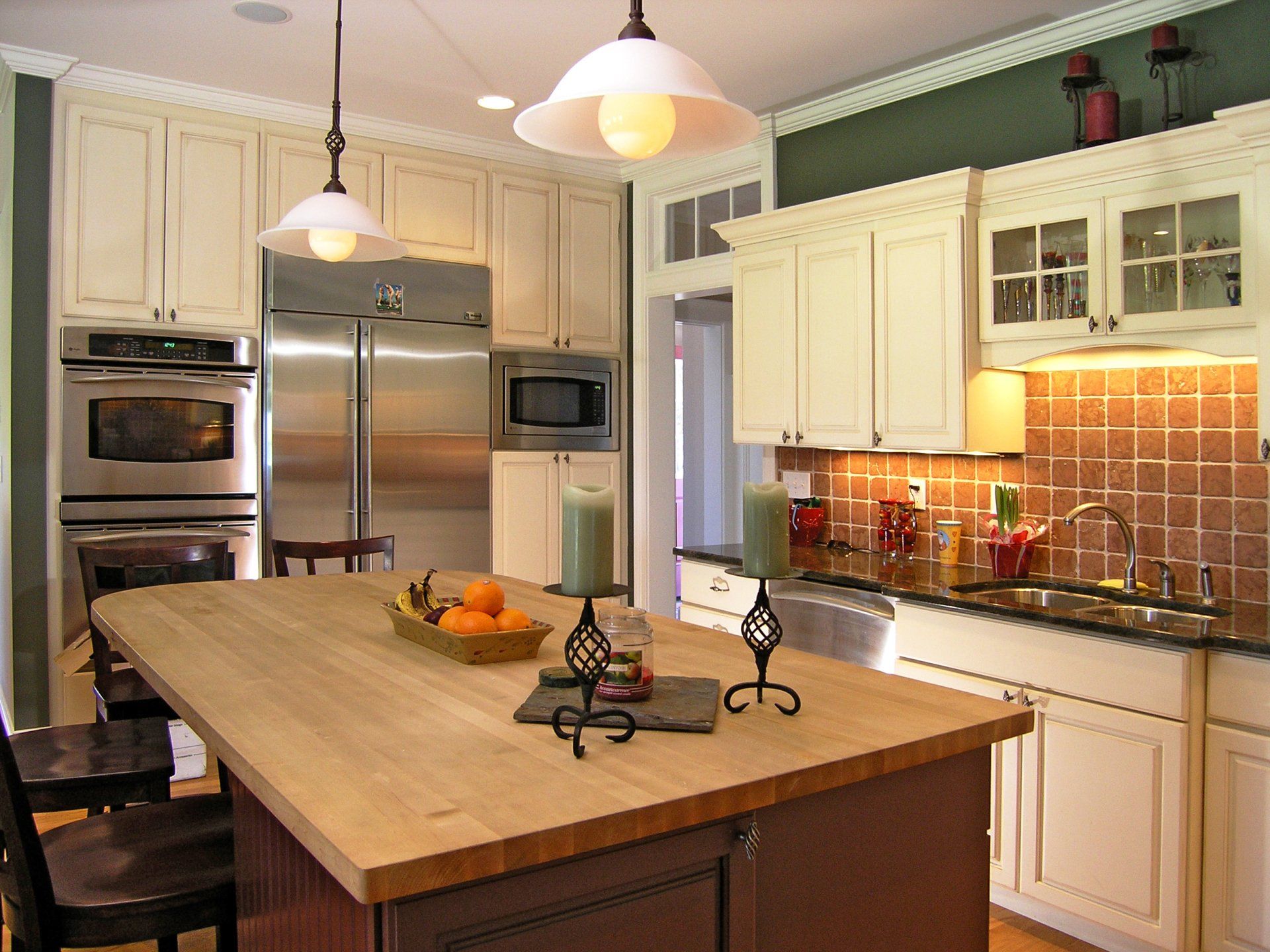 Bright kitchen with a large island, cream cabinets, stainless steel appliances, and hanging pendant lights.