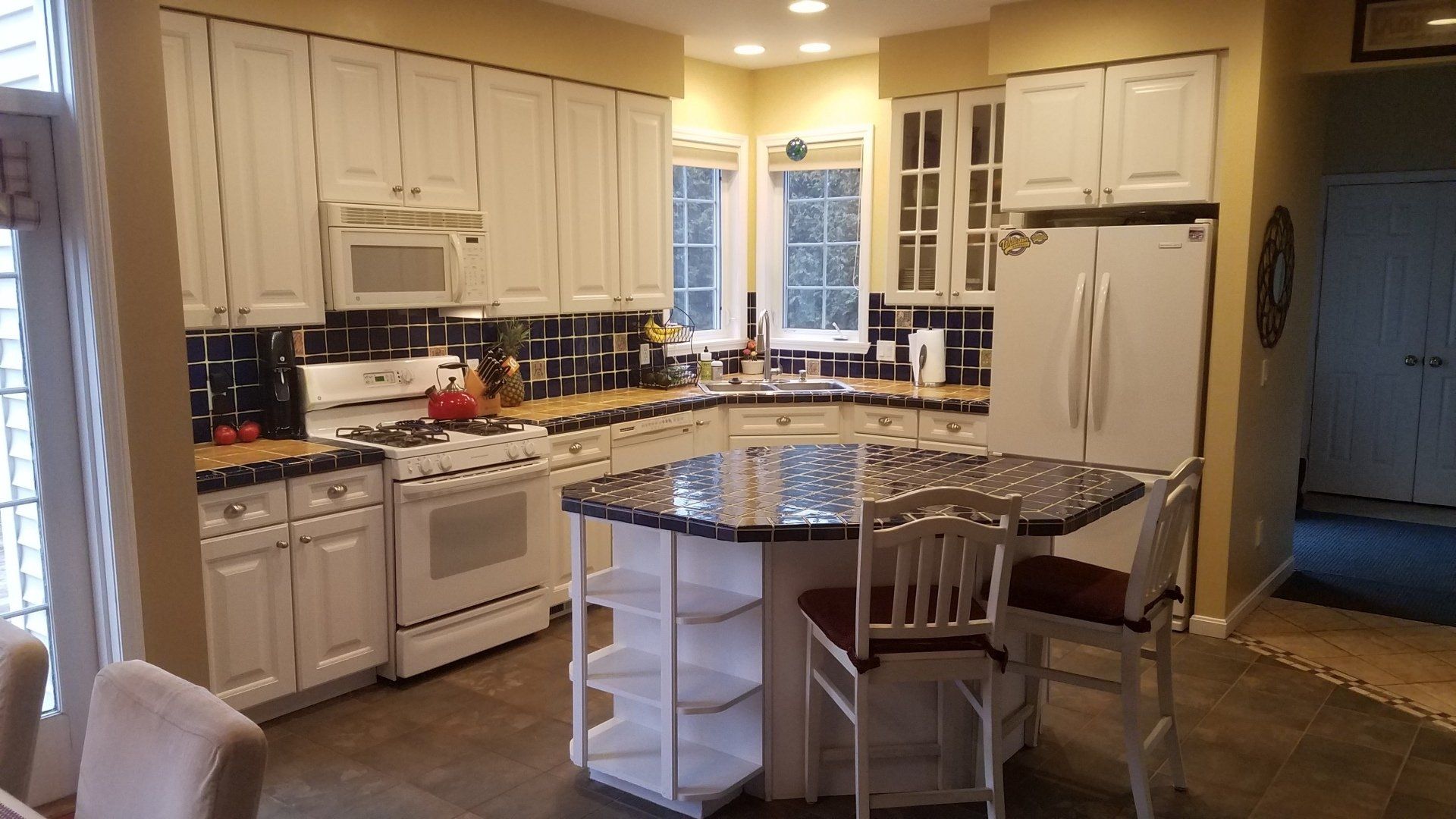 Bright kitchen with white cabinets, granite island, and a breakfast table by the window.