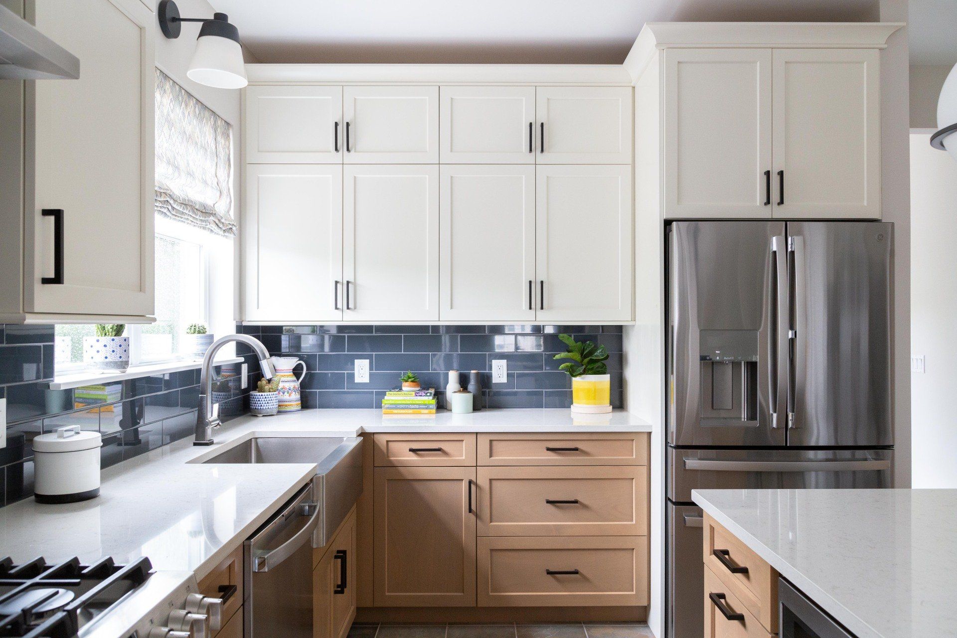 Bright modern kitchen with white cabinets, stainless refrigerator, and light wood drawers