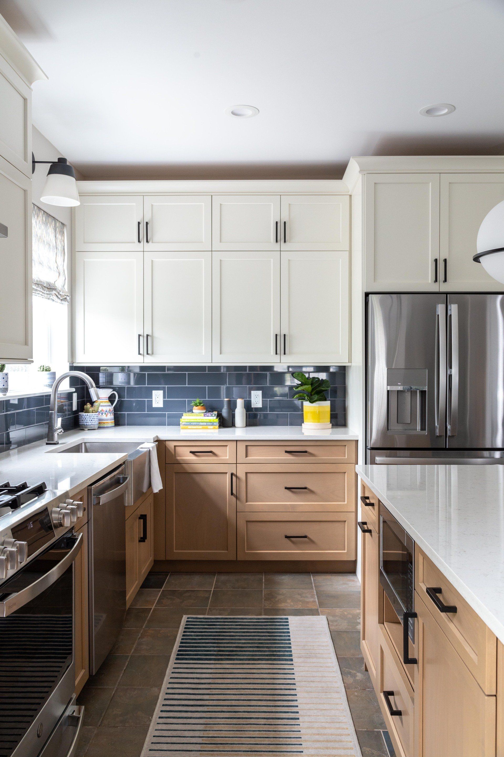 Modern kitchen with white cabinets, stainless steel fridge, wood island, and striped runner rug.