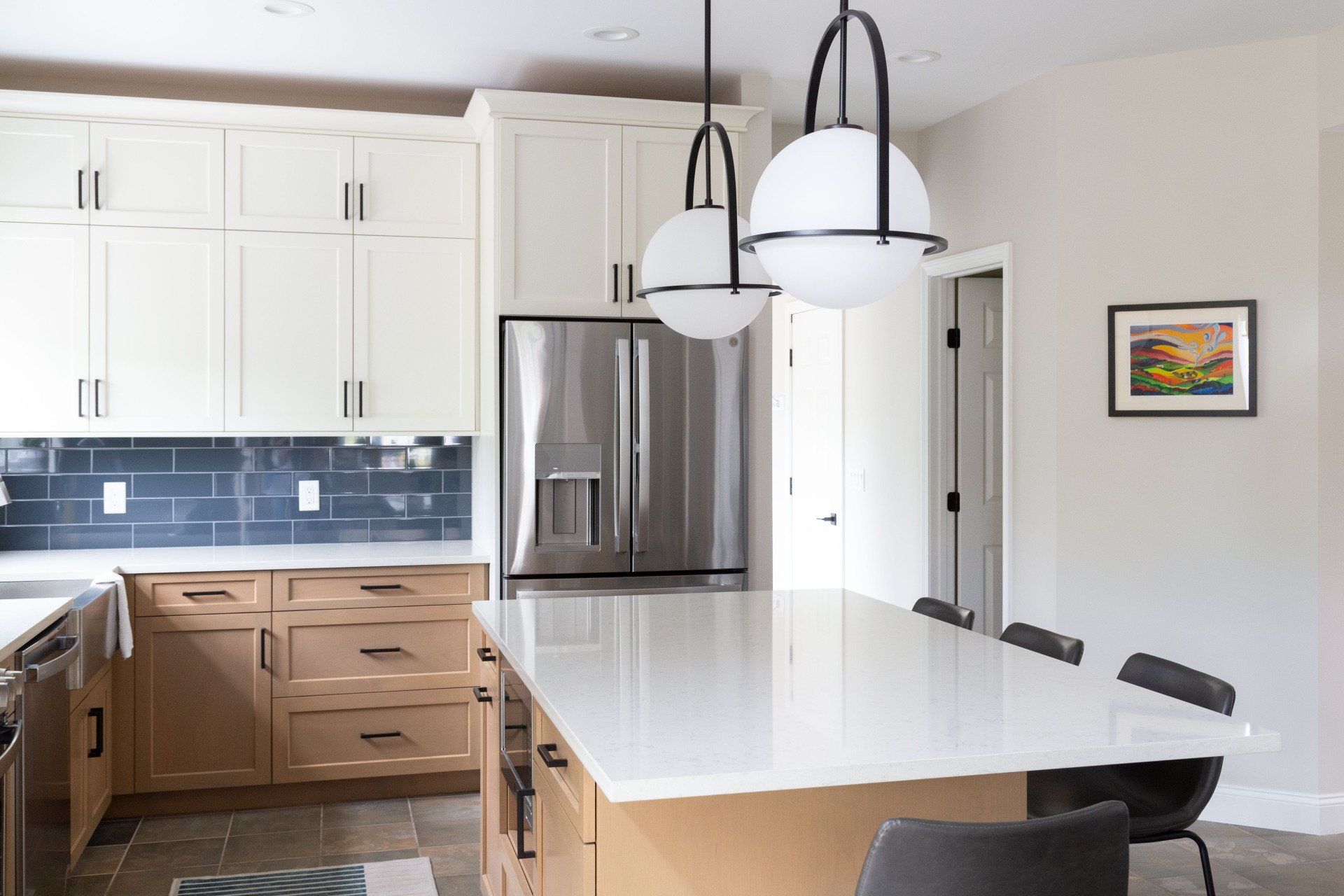 Modern kitchen with white cabinets, stainless steel fridge, island, pendant lights, and dining table