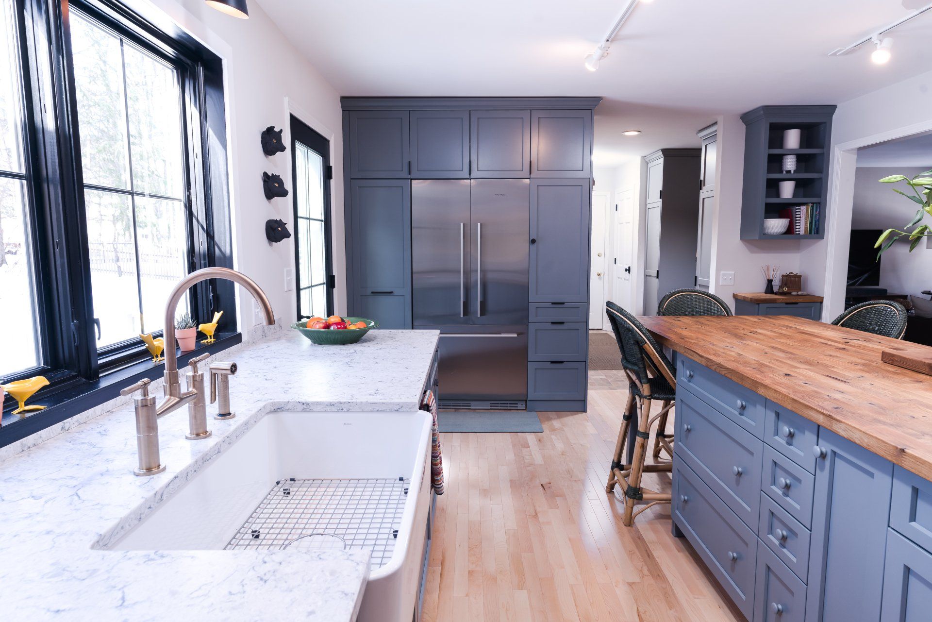 Modern kitchen with white counters, blue cabinets, wood island, and large window