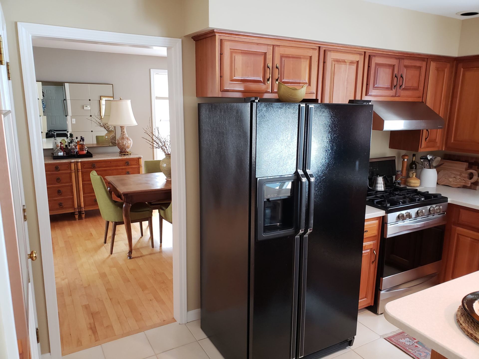 Kitchen with black refrigerator, wood cabinets, and a view into a dining room through a doorway