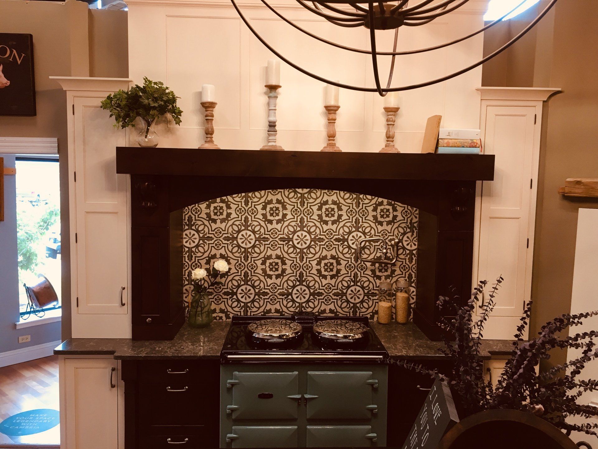 Kitchen with dark wood cabinets, patterned tile backsplash, and decorative shelves under a large hanging light fixture
