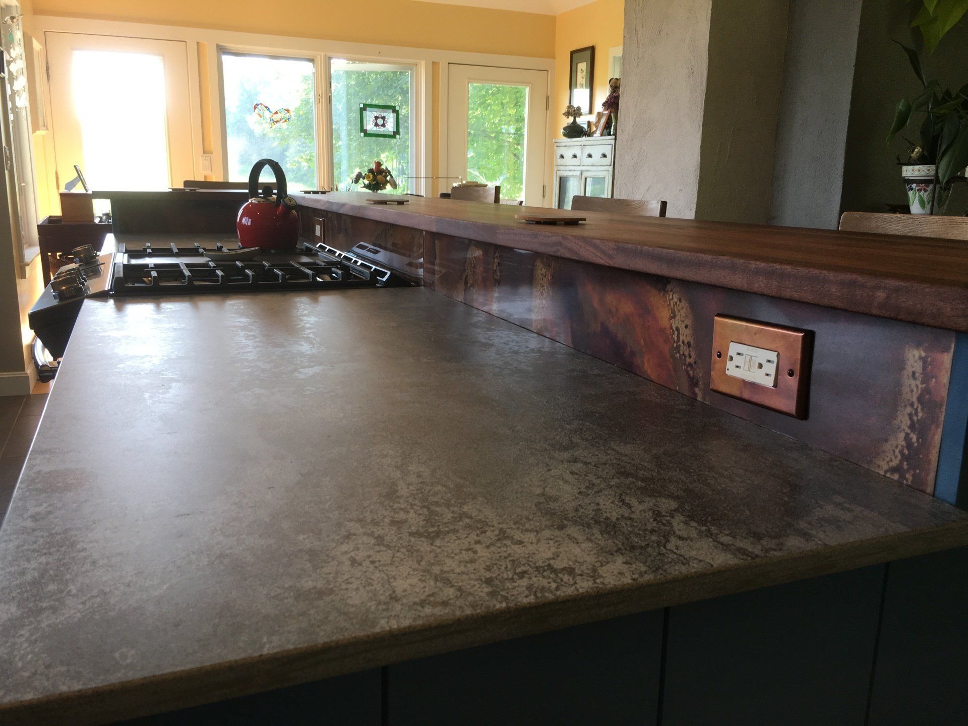 Kitchen counter with gas stove, textured countertop, and large windows overlooking greenery