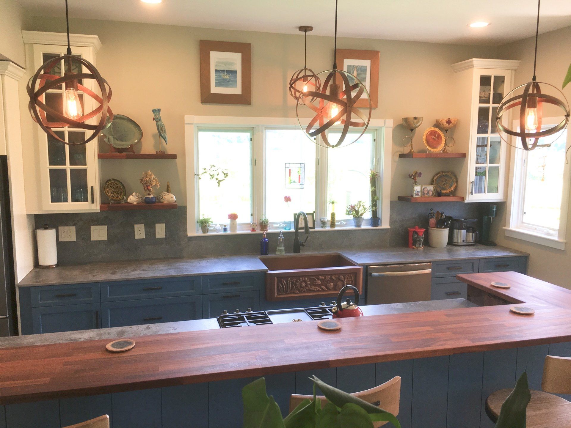 Rustic kitchen with dark blue cabinets, wood island, pendant lights, and a bright window over the sink
