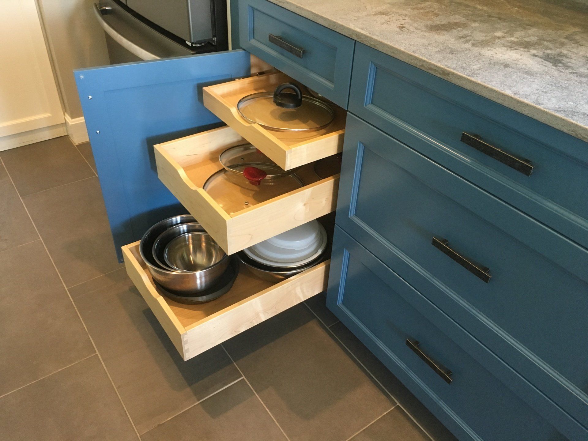 Kitchen cabinet drawers used as pull-out shelves holding bowls and dishes