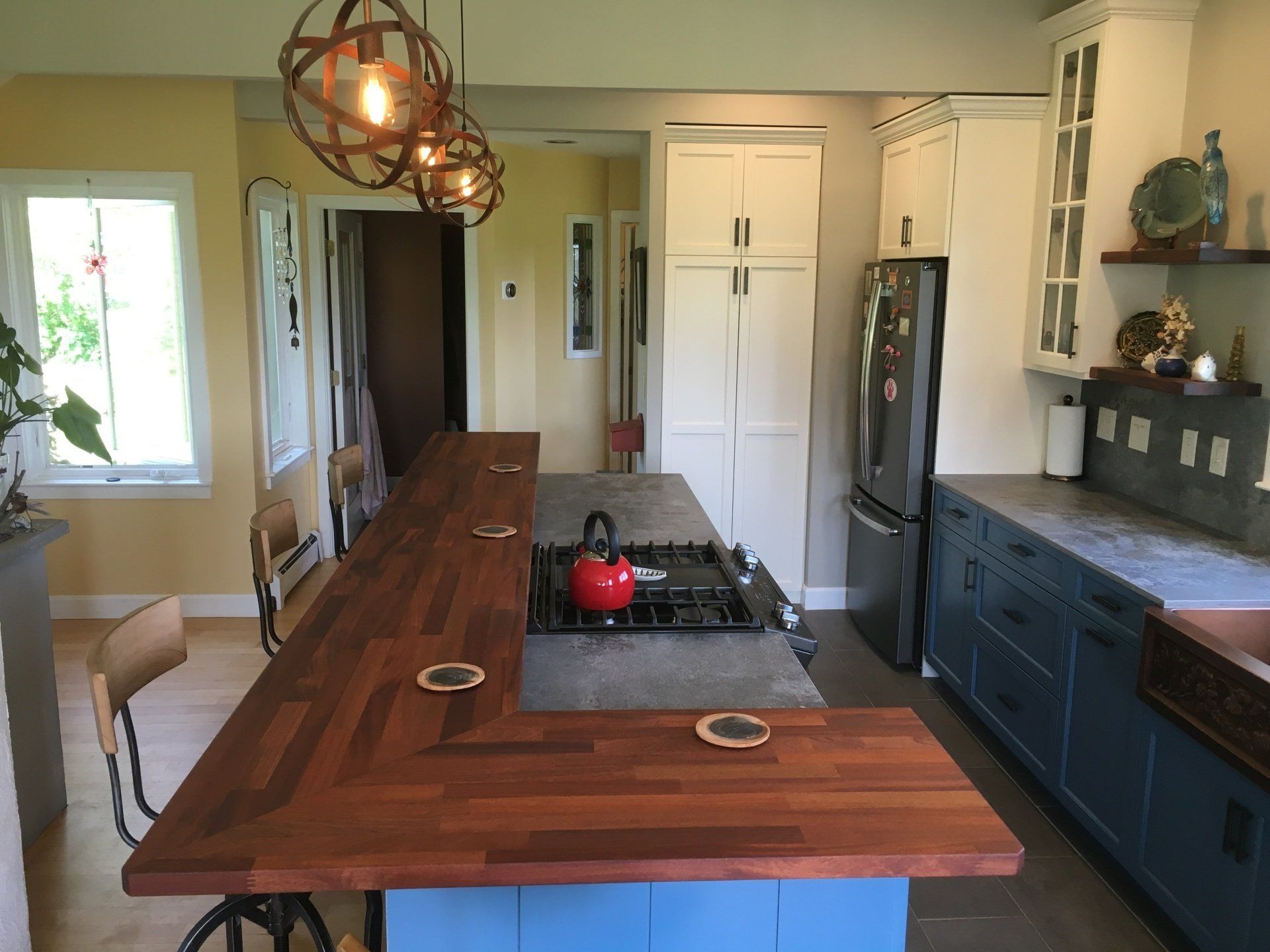 Modern kitchen with large wooden island, pendant lights, and blue cabinets