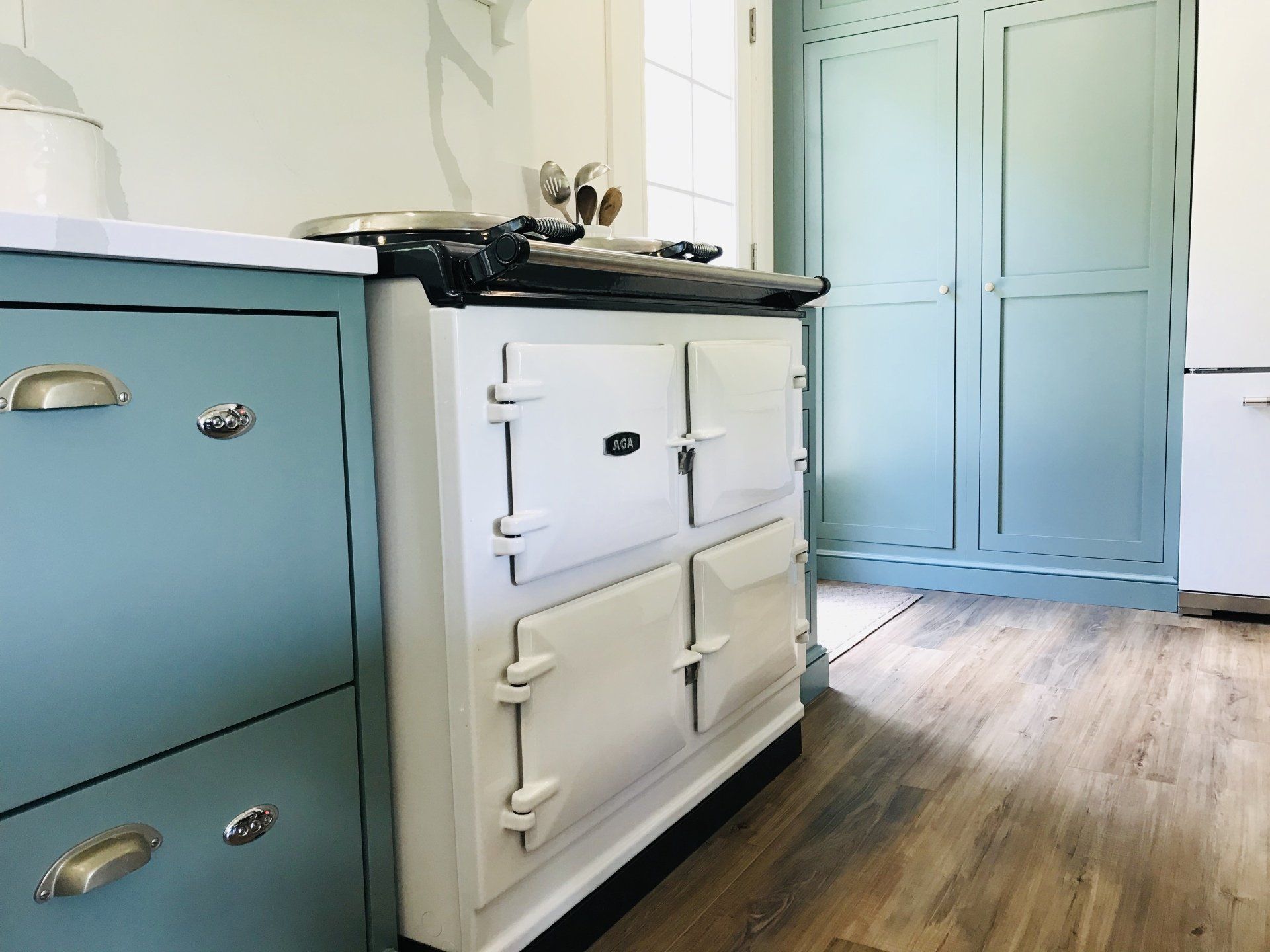 Pastel blue and white kitchen cabinets with a wooden floor in a bright room
