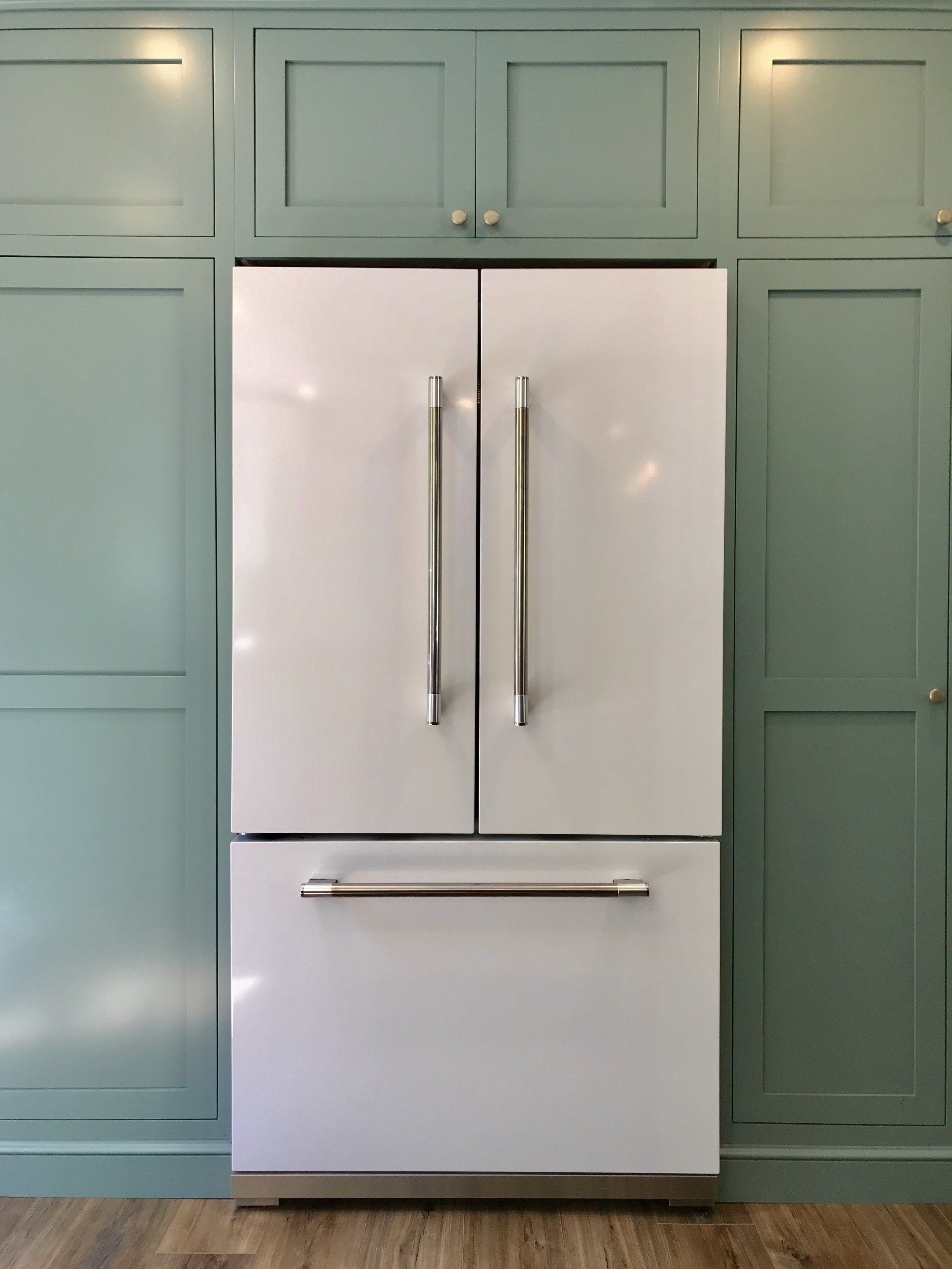 White French-door refrigerator built into mint green kitchen cabinets.