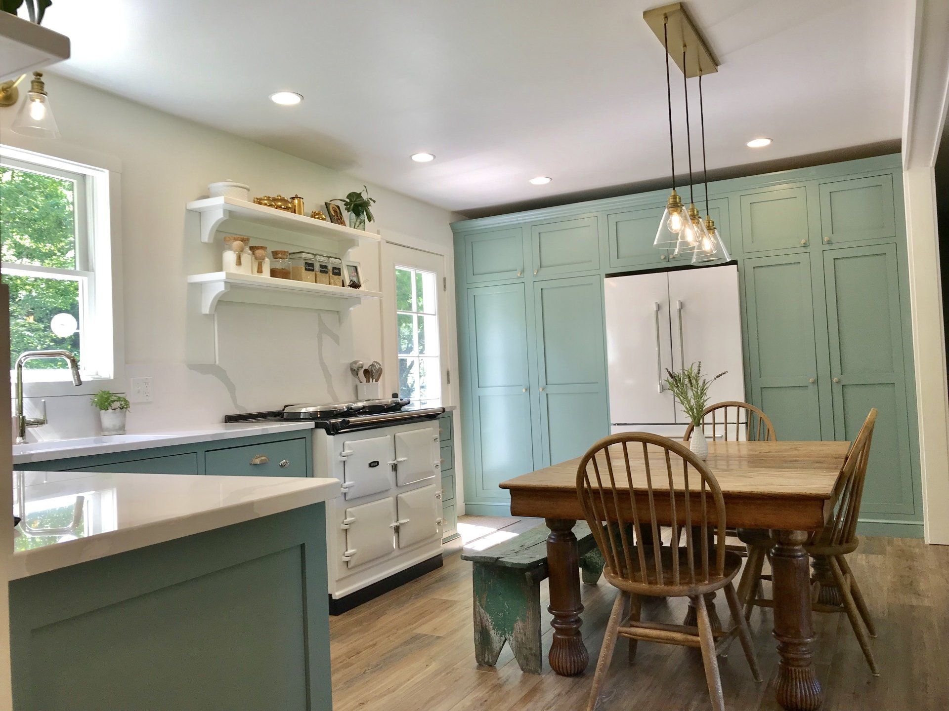 Bright kitchen with mint cabinets, farmhouse table, and a hanging pendant light