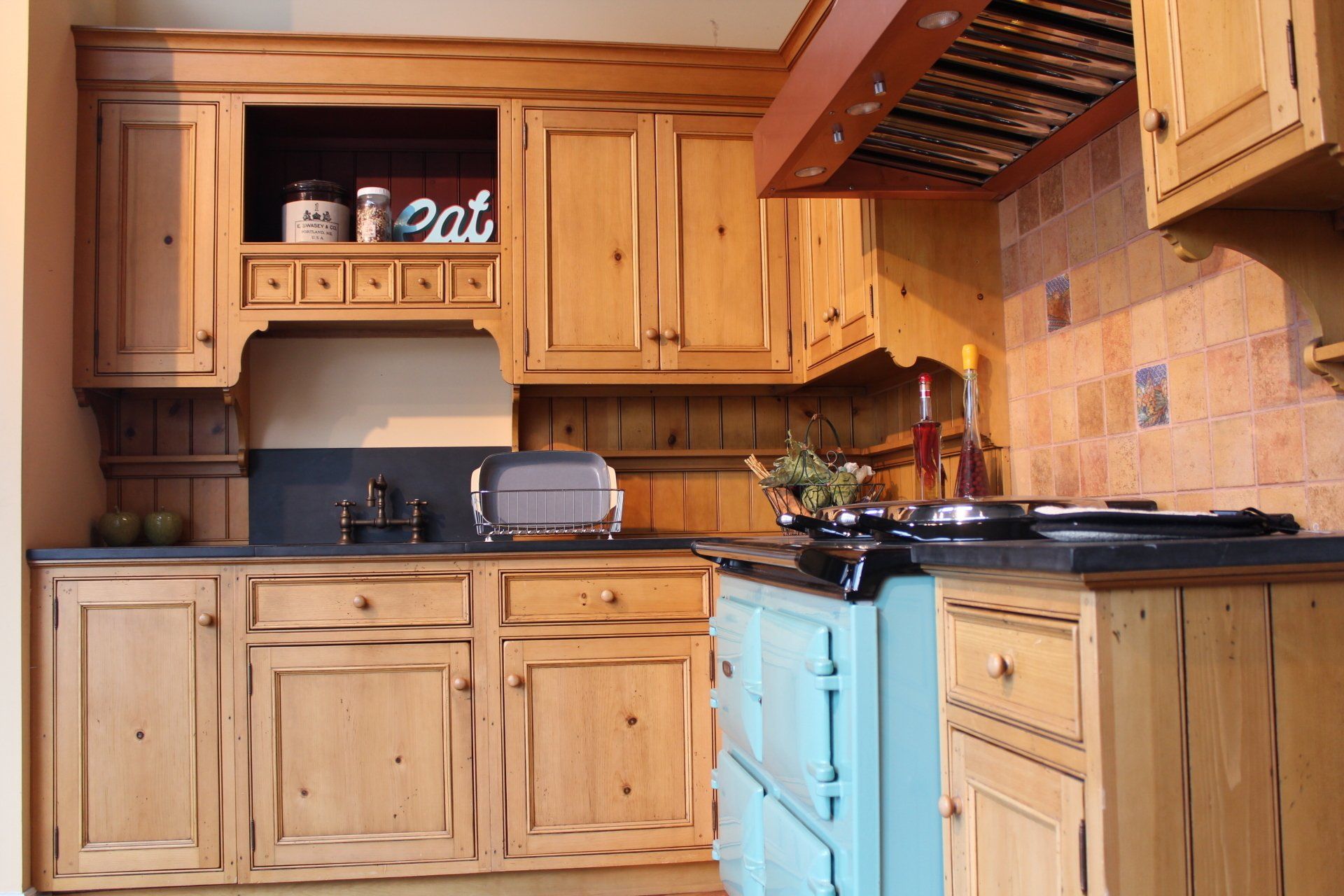 Wooden kitchen with blue stove, cabinets, tiled backsplash, and small appliances