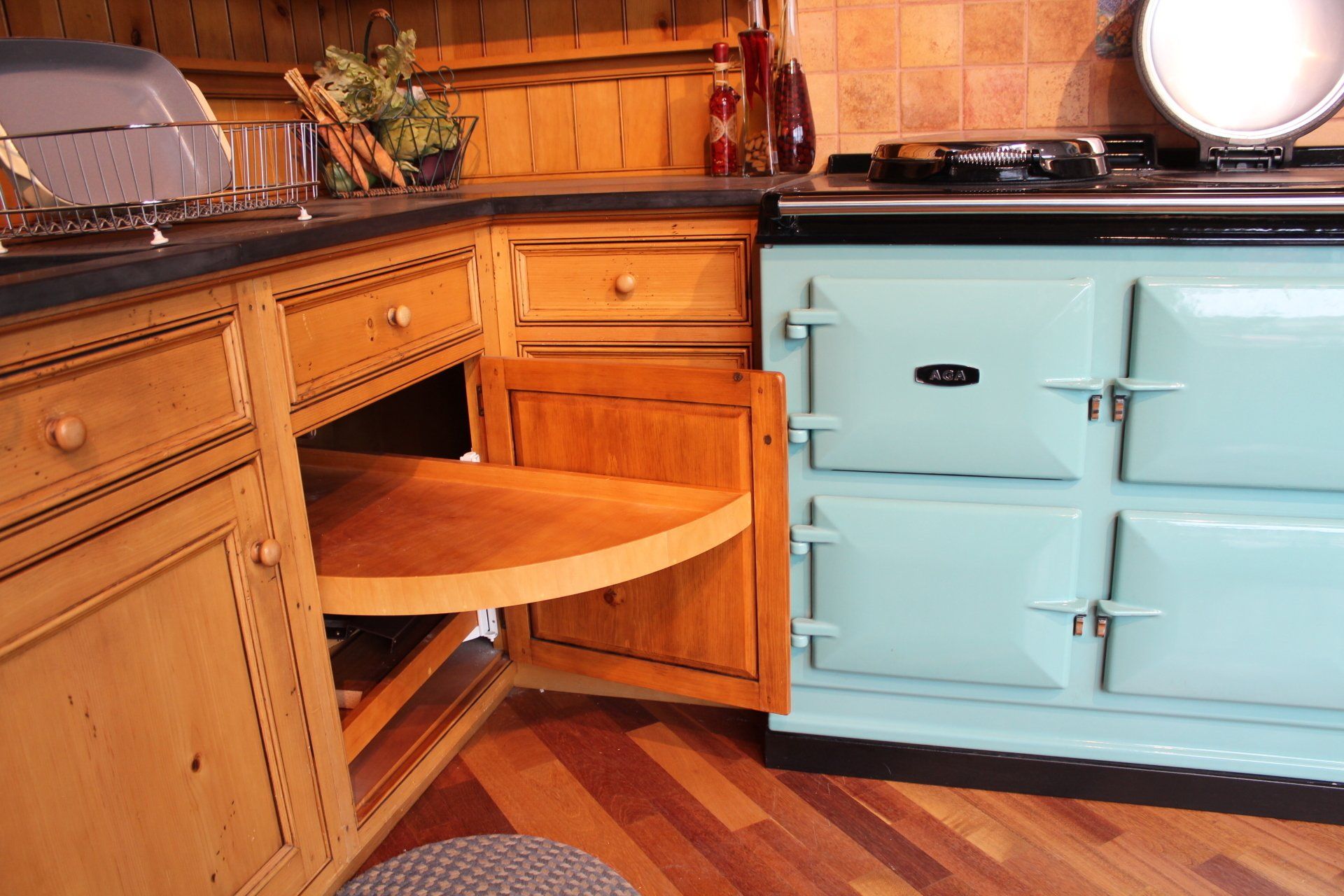 Rustic kitchen corner with a built-in wooden desk and chair beside a light blue cabinet and stove.