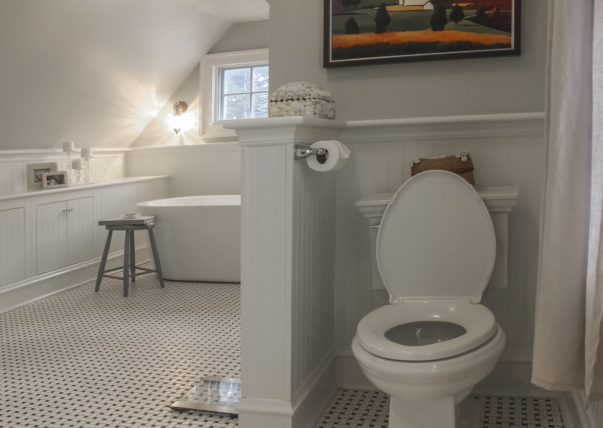 Bright bathroom with open toilet, hex tile floor, window, and bathtub stool in a white interior