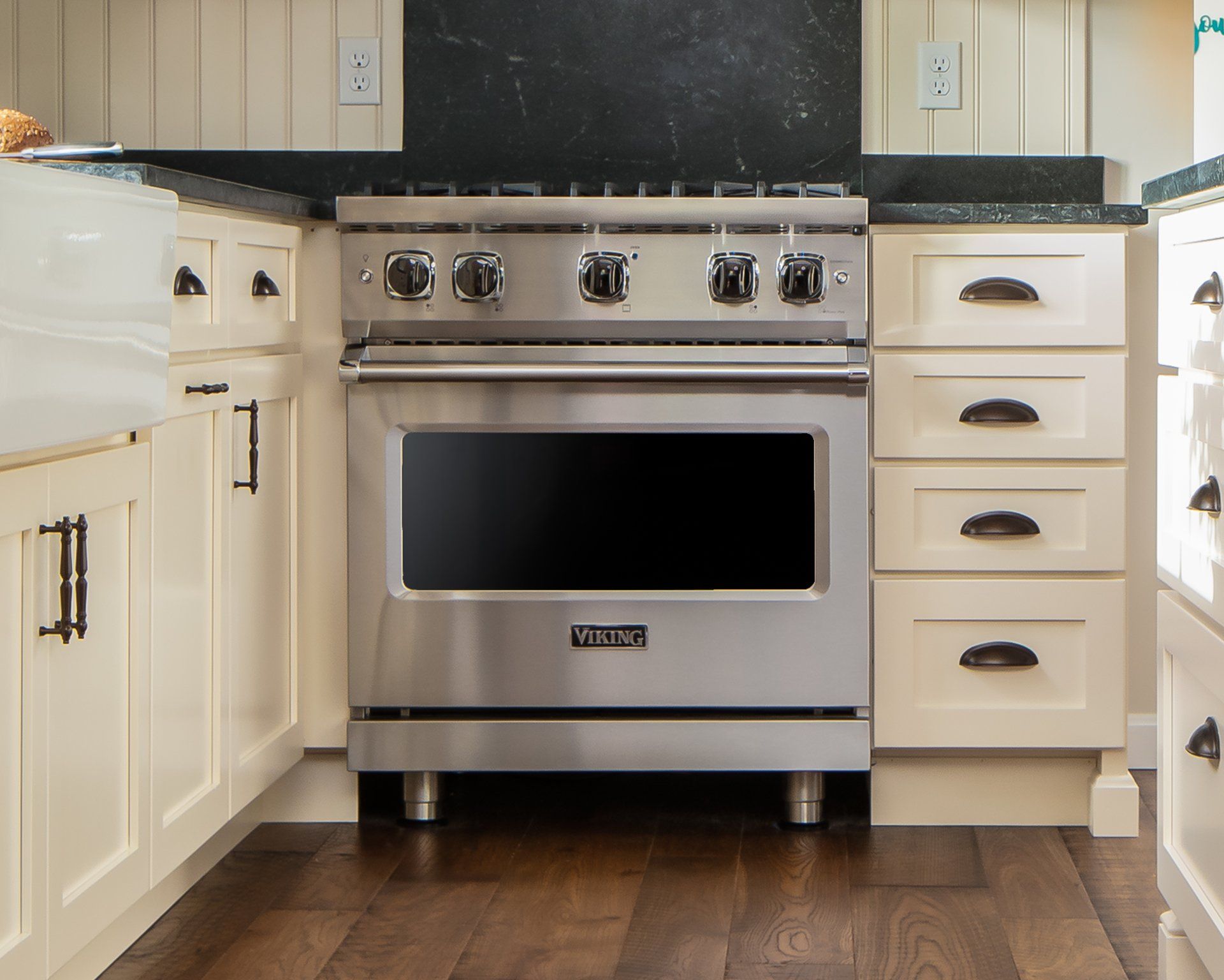 Modern kitchen with stainless steel range, cream cabinets, and dark wood floor