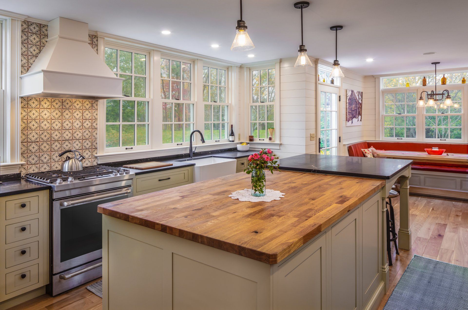 Bright modern kitchen with a large wooden island, pendant lights, and a windowed breakfast nook