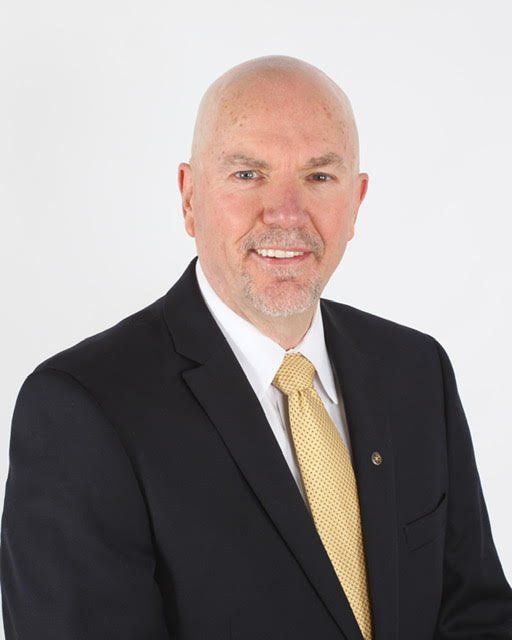 James Bailey, LMHC, CADC II, CSAT Co-Founder, New England Recovery Associates | Serving Hingham, Greater Boston, South Shore to Cape Code, NE Rhode Island A professional headshot of a smiling person wearing a dark blazer, white button-down shirt, and a gold-patterned necktie.