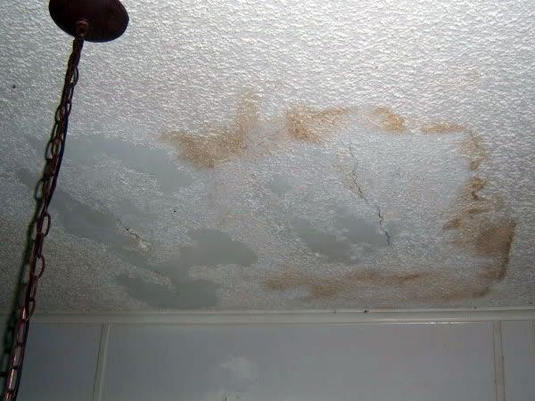 A ceiling with stains on it and a chain hanging from it.